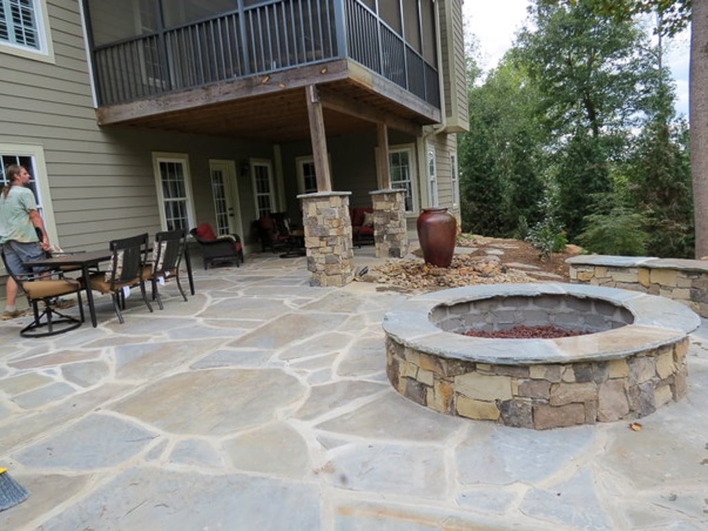 Residential landscaping. Fire pit on patio with worker finishing. Outdoor Fireplaces