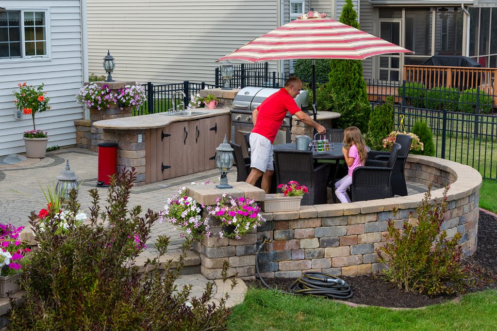 Residential landscaping. Dad cooking outdoors for daughter. L-shaped kitchen