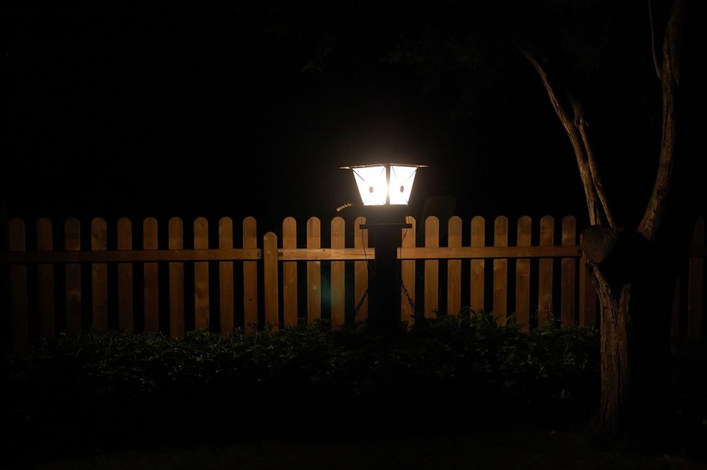 Wooden fence with a glowing decorative lamp.