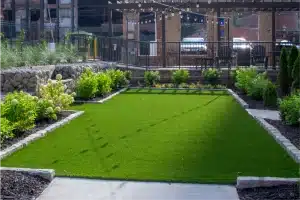 Beautiful commercial landscaping with a grassy area, bench, and fence.