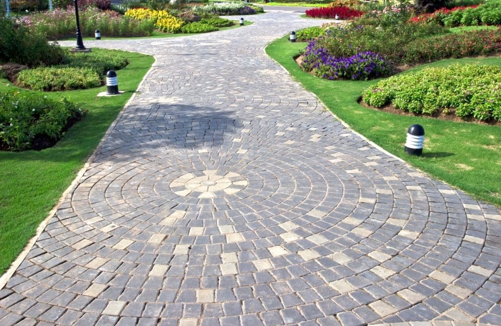 Stone garden path with circular patterns, grass, and flowers