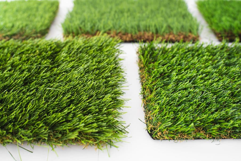 Close-up of various artificial grass samples on a white background.