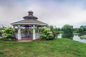 White gazebo by pond surrounded by flowers