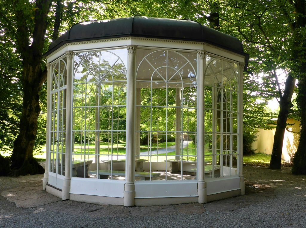 White enclosed gazebo with glass panels in garden