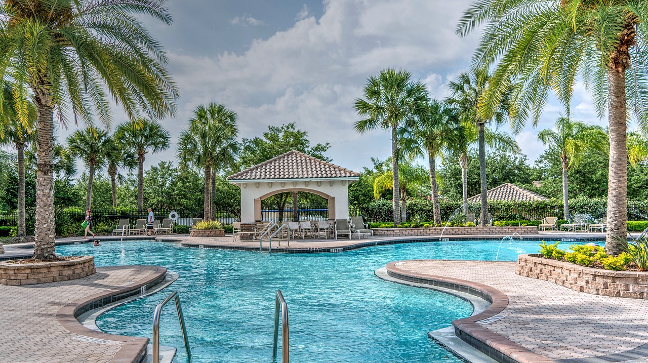 Gazebo by pool with palm trees in backyard