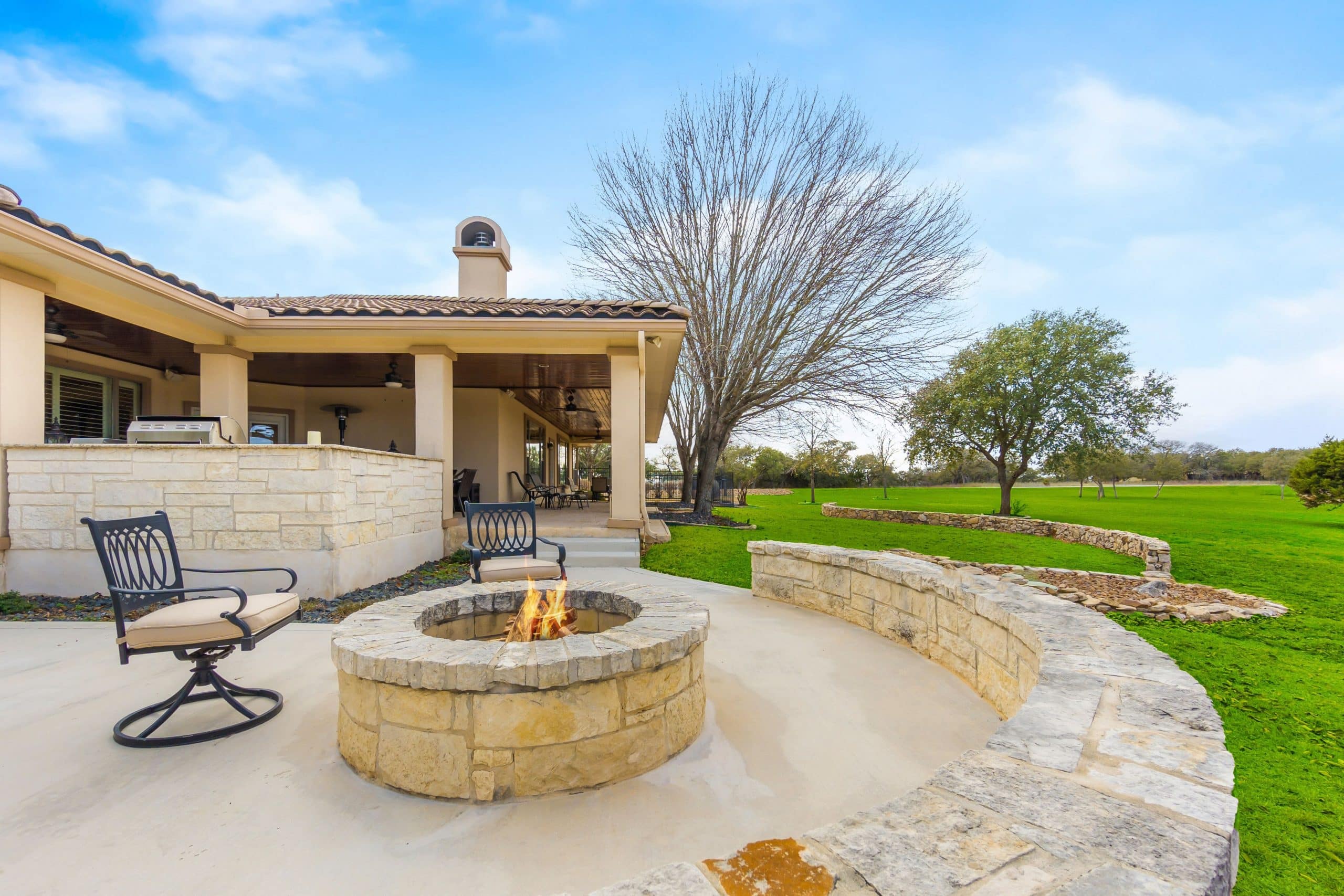 A backyard patio with a fire pit surrounded by landscape stepping stones.