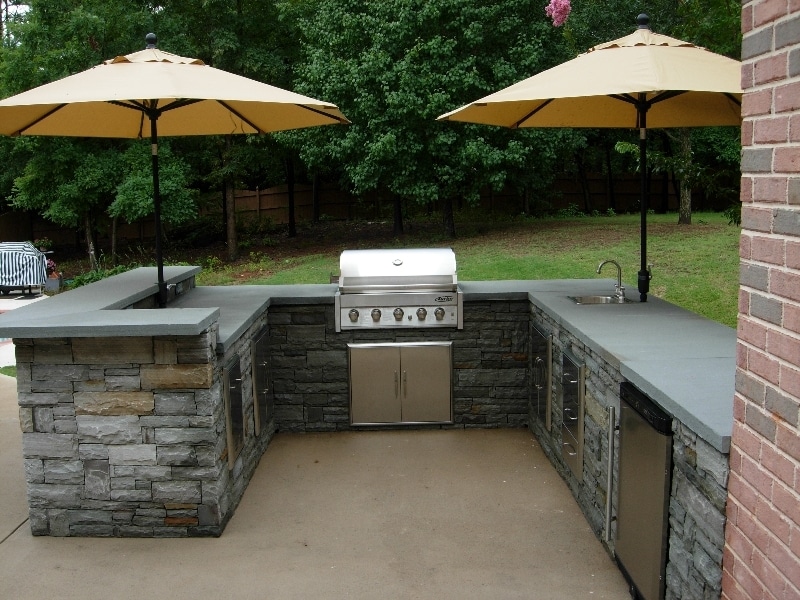 U-shaped outdoor kitchen with grill and sink setup.